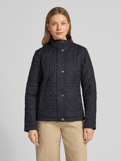 Frauenmodel trägt Steppjacke mit Stehkragen und Eingrifftaschen von Fuchs Schmitt, dunkelblau, strukturierte Oberfläche, Regular Fit, Ganzkörperansicht von vorne. Rückenlänge 64 cm, Schulterbreite 43 cm, Brustweite 49 cm, Ärmellänge 65 cm.