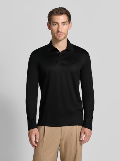 Männermodel trägt Slim Fit Poloshirt aus Lyocell-Mix von Emporio Armani in Schwarz, Baumwoll-Anteil, Polokragen, Ganzkörperansicht von vorne.