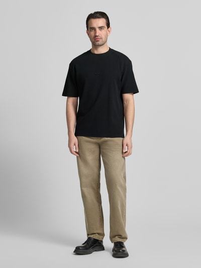 Männermodel trägt Regular Fit T-Shirt aus reiner Baumwolle Modell 'DAFFL' von HUGO in Schwarz, unifarben, Rundhals, Ganzkörperansicht von vorne.