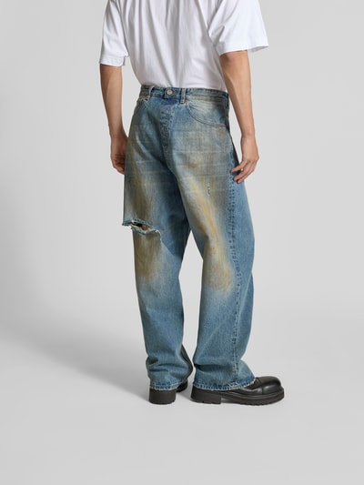 Männermodel trägt Loose Fit Jeans aus Baumwolle von VETEMENTS im Destroyed-Look, 5-Pocket-Design, mittleres Blau, Ganzkörperansicht Rückansicht.