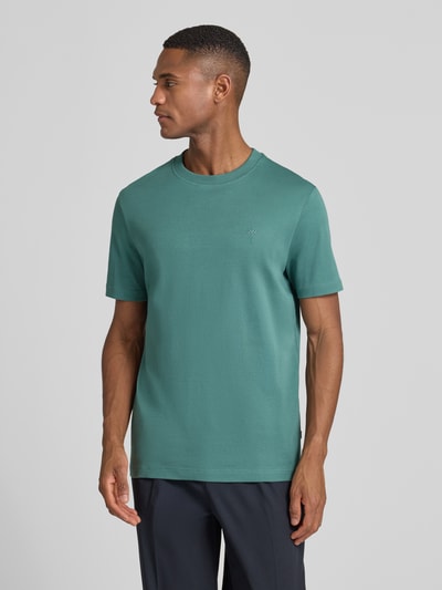 Männermodel trägt T-Shirt mit Label-Stitching Modell 'Priamo' von JOOP! Collection in Grün, Baumwolle, Regular Fit, Ganzkörperansicht von vorne.