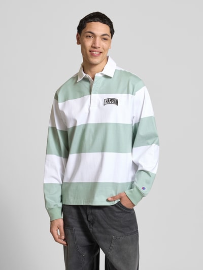 Männermodel trägt Relaxed Fit Poloshirt aus Baumwolle von CHAMPION in Hellgrün und Weiß mit Blockstreifen, Langarm, Label-Stitching, Nahaufnahme Oberkörper.