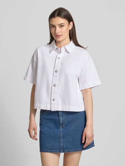 Frauenmodel trägt Loose Fit Jeansbluse aus reiner Baumwolle Modell 'SKY' von Pieces in Weiß, Denim-Optik, Hemdkragen, Kurzarm, Ganzkörperansicht von vorne.