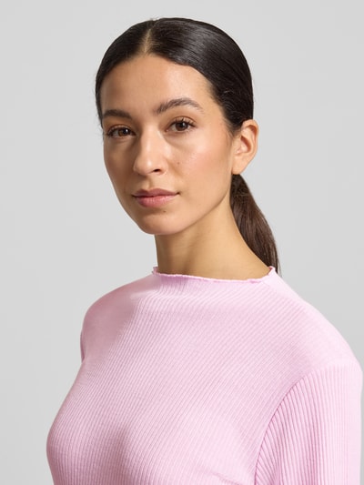 Modelka kobieca nosi Slim Fit Langarmshirt mit Viskose-Anteil od s.Oliver RED LABEL, różowy rippstrick, detal frill, unikolor, krój slim fit, zbliżenie na górną część ciała.