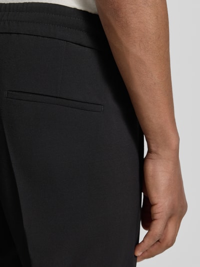 Männermodel trägt Hose mit Gesäßtaschen Modell 'CHASY' von Drykorn, schwarzer Baumwoll-Mix, Slim-Fit, Nahaufnahme Oberkörper, Kontext: Herren Hose, Material-Mix mit Baumwoll-Anteil, Bundweite 33 cm, Innenbeinlänge 64 cm, Größe 32/32.