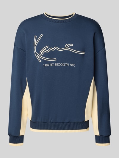 Produktfoto, Sweatshirt mit Label-Stitching von Karl Kani, bawełniany miks, krój regular fit, okrągły dekolt, długość tyłu w rozmiarze M: 66 cm, długość rękawa w rozmiarze M: 56 cm, granatowy z kremowymi wstawkami, faktura gładka