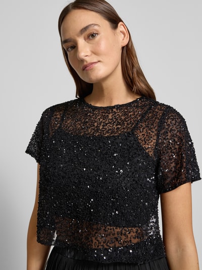 Modelka kobieca nosi Cropped T-Shirt aus Mesh mit Pailletten od LACE & BEADS, czarny, półprzezroczysty, okrągły dekolt, siateczka, cekiny, widok na górną część ciała z przodu.