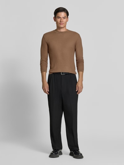 Männermodel trägt Strickpullover mit Struktur-Muster von Emporio Armani in Braun, taillierter Schnitt, Rundhalsausschnitt, Ganzkörperansicht von vorne.
