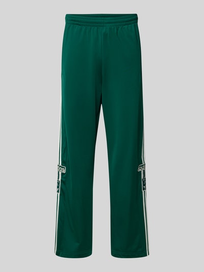 Produktfoto, grüne Sweatpants mit elastischem Bund von adidas Originals, weiter Schnitt, weiße Streifendetails, glatte Textur, Label-Stitchings