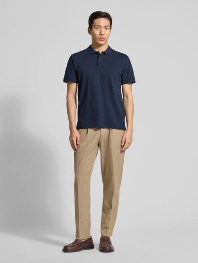Męski model ma na sobie Regular Fit Poloshirt aus reiner Baumwolle von Tom Tailor, granatowy, krój regular fit, bawełna, przód, zdjęcie całej sylwetki.