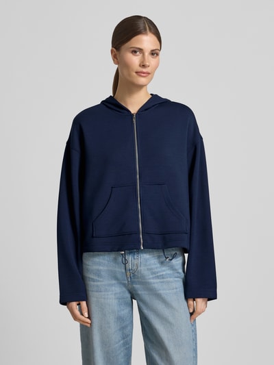Modelka prezentuje Regular Fit Sweatjacke mit Kapuze von Christian Berg Woman z elastycznej mieszanki materiałów z domieszką modalu, krój regular fit, kaptur, podzielona kieszeń kangurka, pas z tunelem, widok całej sylwetki z przodu.
