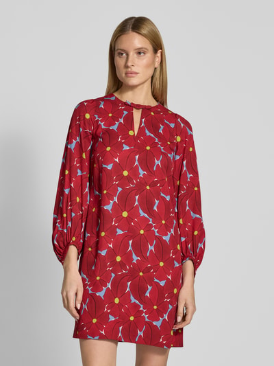 Frauenmodel trägt Tunikakleid aus Viskose mit Schlüsselloch-Ausschnitt von Luisa Cerano, rotes Muster, knielang, Nahaufnahme Oberkörper.