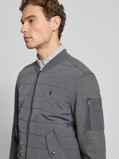 Mannenmodel draagt Regular Fit Steppjacke aus Baumwoll-Mix van Polo Ralph Lauren in uni grijs met collegekraag en label stitching, nahaufnahme bovenlichaam.