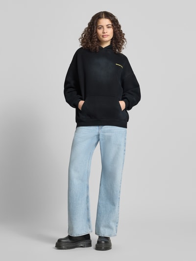 Frauenmodel trägt Hoodie mit Logo-Stitching von ANOTHER COTTON LAB aus mieszanka bawełny, luźny krój, kaptur, kieszeń kangurka, widok całej sylwetki z przodu