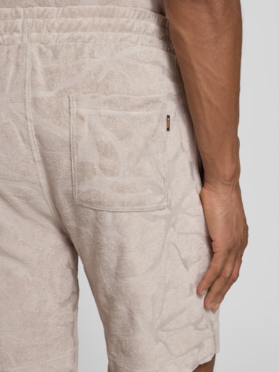 Männermodel trägt Regular Fit Sweatshorts aus Baumwoll-Mix Modell 'SE_FLOWER' von BOSS Orange, Frottee, unifarben, Detailaufnahme Rückansicht.
