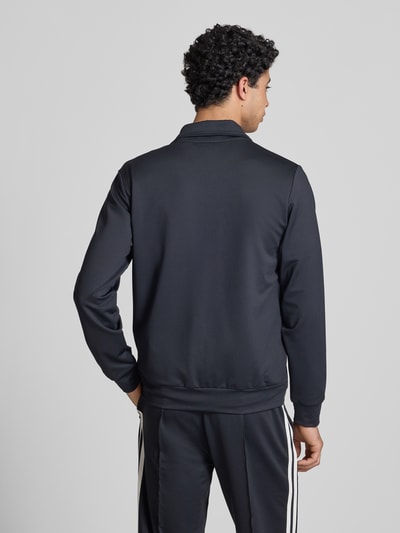 Männermodel trägt Sweatjacke mit Reißverschlusstaschen Modell 'TOSCIANA' von Ellesse, Material-Mix, schwarze Farbe, Rückenansicht.