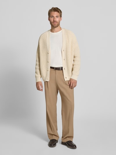 Männermodel trägt Regular Fit Strickjacke aus Baumwoll-Mix Modell 'Andemo' von BOSS Orange in Beige, lockere Strickstruktur, Ganzkörperansicht von vorne.