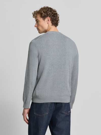 Männermodel trägt grauen Regular Fit Pullover aus Baumwoll-Mix von Lacoste, kombiniert mit blauen Jeans, Ganzkörperansicht Rückansicht. Herren Pullover von Lacoste.