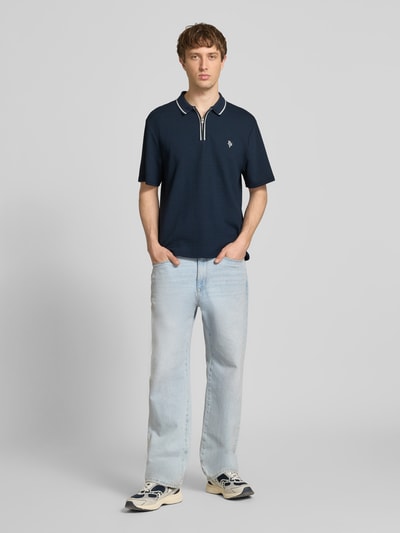 Männermodel trägt Regular Fit Poloshirt mit Reißverschluss und Label-Stitching von REVIEW, Material-Mix, Strukturmuster, Ganzkörperansicht von vorne.