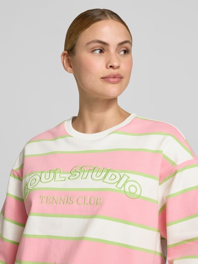 Frauenmodel trägt Cropped Boxy Fit Sweatshirt mit Label-Stitching von Smith and Soul aus Baumwoll-Elasthan-Mix, rosa und grün gestreift, Rundhalsausschnitt, Nahaufnahme Oberkörper.