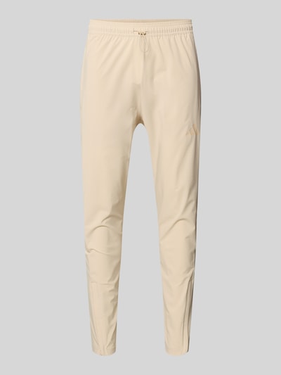 Produktfoto, Jogpants mit elastischem Bund von adidas Sportswear, beżowy kolor, prosty krój, nadruk z logo, materiał z dodatkiem stretchu, długość nogawki 71 cm w rozmiarze M, widoczny tunel na sznurek