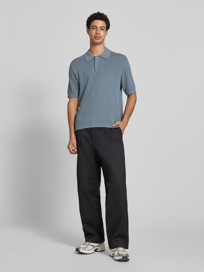 Männermodel trägt Regular Fit poloshirt aus puur katoen van Marc O'Polo Denim, effen kleuren, labelpatch, polokraag, V-hals, korte knoopsluiting, korte mouw met geribd mouwboord, rompzoom geribd, knitwear, ganzkörperansicht van voren.