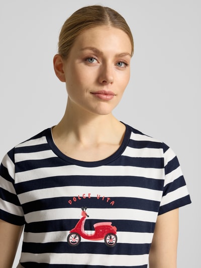 Vrouwenmodel draagt T-shirt met motiefprint en ronde hals van More & More, mix van katoen en elastaan, regular fit, ruglengte maat 36: 63 cm, navy-wit gestreept met rood motief, nahaufnahme bovenlichaam.