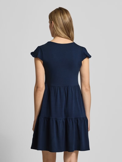 Frauenmodel trägt Minikleid im Stufen-Look mit V-Ausschnitt von REVIEW aus Baumwoll-Elasthan-Mix in Dunkelblau, A-Linie, Ganzkörperansicht Rückansicht.