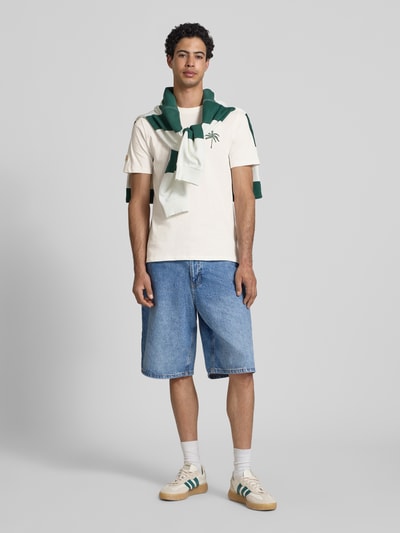 Männermodel trägt T-Shirt mit Motiv-Print Modell 'SUN PALMS' von Blend in Beige, kombiniert mit Jeansshorts, Regular Fit, Ganzkörperansicht von vorne.