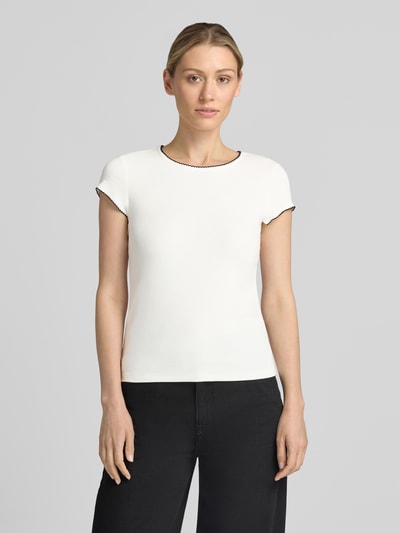 Frauenmodel trägt Slim Fit T-Shirt mit Viskose-Anteil von Comma, Elastischer-Material-Mix, Butterfly-Saum, Rundhalsausschnitt, kurzärmelig, Rückenlänge bei Größe 36: 52 cm, weiße Grundfarbe, schwarze Details, glatte Textur, Ganzkörperansicht von vorne.