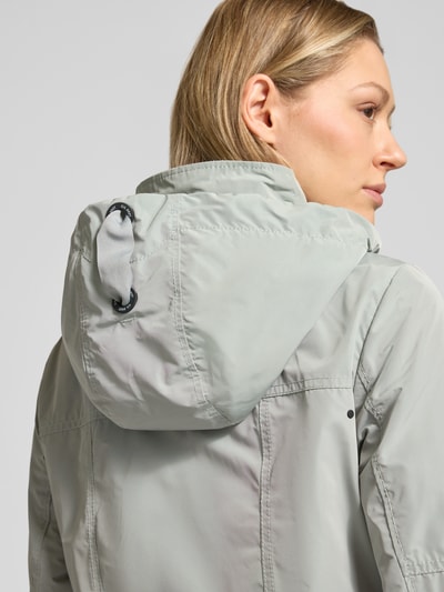 Frauenmodel trägt Weather Protection Jack mit Reißverschlusstaschen von Gil Bret, hellgraue Kapuzenjacke, glatte Oberfläche, Detailaufnahme Rückansicht, Regular Fit, sichtbarer Tunnelzug an der Kapuze