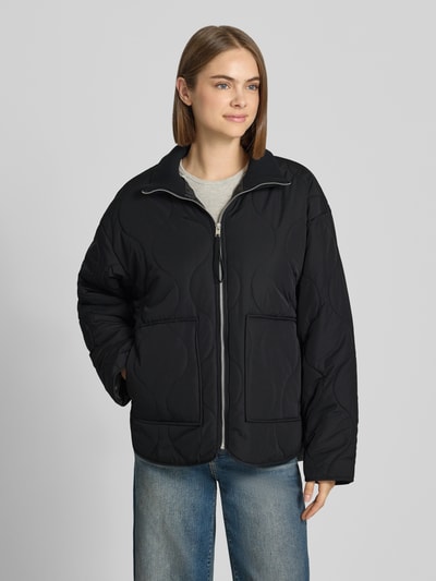 Vrouwenmodel draagt gewatteerd jack van JJXX, Model 'SERENA', doorgestikte naden, gebreide opstaande kraag, ritssluiting, steekzakken, loose fit, zwart, voorkantaanzicht, ruglengte maat S 89 cm, schouderbreedte 58 cm, borstwijdte 57 cm, mouwlengte 55 cm.