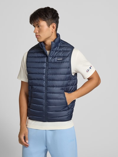Männermodel trägt Steppweste mit Reißverschlusstaschen Modell 'ELVIS' von JACK & JONES in Dunkelblau, glatte Oberfläche, Ganzkörperansicht von vorne. Kontext: Regular Fit, Stehkragen, Reißverschluss, Label-Detail, Rückenlänge 67 cm, Schulterbreite 41 cm, Brustweite 54 cm.