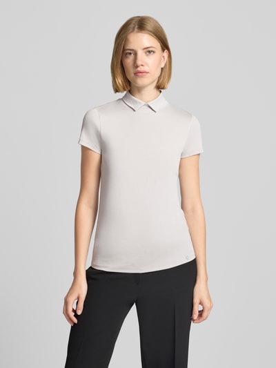 Frauenmodel trägt Slim Fit T-Shirt mit hochschließendem Polokragen von Marc Cain, Baumwoll-Elasthan-Mix, hell, 1/2-Arm, Ganzkörperansicht von vorne.