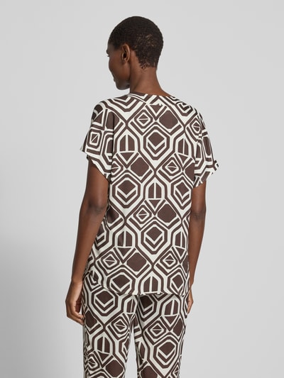 Frauenmodel trägt Regular Fit Bluse aus Viskose Modell 'Amber' von TONI im Allover-Look mit V-Ausschnitt, Rückenlänge 63 cm, Ärmellänge 15 cm, Geometrie-Muster in Braun und Weiß, Ganzkörperansicht Rückansicht.
