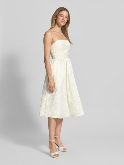 Frauenmodel trägt Minikleid mit floralem Allover-Stitching von Hey Kyla, cremefarben, tailliert, schulterfrei, ausgestellte Passform, Ganzkörperansicht von vorne.