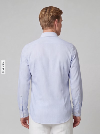 Männermodel trägt Slim Fit Businesshemd aus reiner Baumwolle Modell 'New Kent' von Seidensticker, zartblau gestreift, Ganzkörperansicht Rückansicht. Herren Businesshemd von Seidensticker.