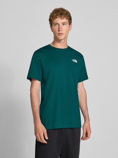 Männermodel trägt t-shirt met labelprint Model 'Evolution' van The North Face in donkergroen katoenmix, regular fit, ruglengte bij maat M 73 cm, frontale borst tot bovenbenen, Ganzkörperansicht von vorne.