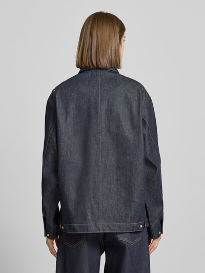 Frauenmodel trägt Regular Fit Jeansjacke mit Logo-Patch Modell 'Arctic' von Carhartt Work In Progress aus dunkelblauer Baumwolle, Rückenansicht.
