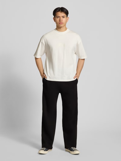 Männermodel trägt Sweatpants mit Logo-Print und Gesäßtasche von REVIEW, Schwarz, Baumwoll-Mix, Gerader-Schnitt, Eingrifftaschen, Ganzkörperansicht von vorne.