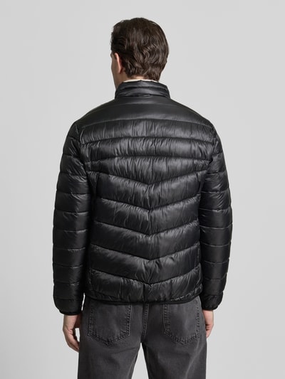 Męski model ma na sobie Regular Fit Steppjacke mit Stehkragen od Tom Tailor, czarna, jednolita, krój regular fit, stójka, suwak, naszywka z logo, elastyczne mankiety i dół, funkcja termoizolacyjna, wodoodporna, kieszenie boczne i na piersi, widok całej sylwetki z tyłu.