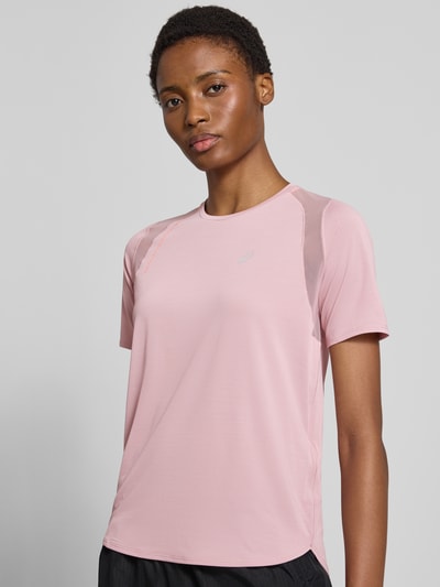 Frauenmodel trägt Regular Fit T-Shirt mit Stretch-Anteil Modell 'Road' von ASICS TIGER in Rosa, reflektierender Logo-Print, Nahaufnahme Oberkörper.