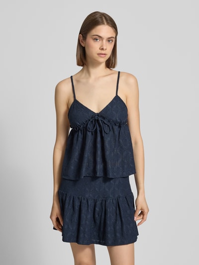Kobiece modelka nosi Babydoll-Top mit Schößchendetail und Lochstickerei od REVIEW, mieszanka materiałów z dodatkiem streczu, krój regular fit, baskinka, haft angielski, długość tyłu w rozmiarze S: 27 cm, kolor ciemnogranatowy, widoczne tekstury, widoczne kształty, przód, zdjęcie całej sylwetki.