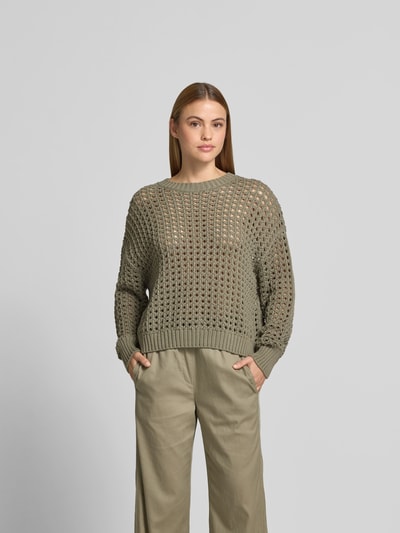 Frauenmodel trägt Relaxed Fit Pullover mit Lochmuster von Juvia aus reiner Baumwolle in Olivgrün, elastische Abschlüsse, Ganzkörperansicht von vorne.