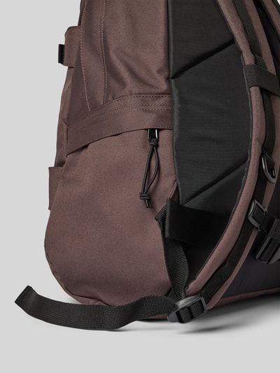 Productfoto, Rucksack met label-details Modell 'KICKFLIP' van Carhartt Work In Progress in bruin en zwart met verstelbare schouderriem, detailopname, hoofdvak met rondom-rits, kliksluitingen en buitenvakken, breedte 36 cm, lengte 48 cm, diepte 18 cm, schouderriemlengte 63 cm.
