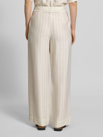Frauenmodel trägt Regular Fit Weite Hose aus Lyocell-Viskose-Mix Modell 'MARIE-JOHANNE' von Selected Femme, efekt: wzór w cienkie prążki, krój regular fit, wysoki stan, szlufki na pasek, wiązany pasek, zapięcie na haftkę i zamek błyskawiczny, wpuszczana kieszeń, mieszanka wiskozy i lyocellu, jasny kolor, szerokie nogawki, Ganzkörperansicht Rückansicht.