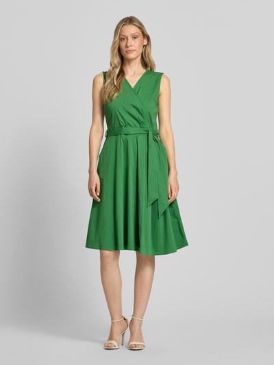Vrouwenmodel draagt Kleid mit V-Ausschnitt in Wickel-Optik van More & More in groen katoenmix, getailleerd, mouwloos design, tailleband, Ganzkörperansicht van voren.