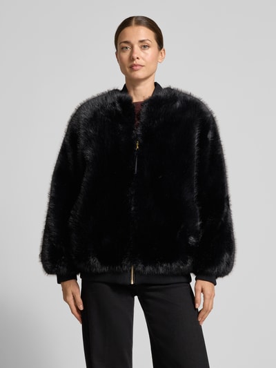 Frauenmodel trägt Jacke aus Kunstfell mit Stehkragen und Reißverschluss von Armani Exchange, schwarz glänzend, Rippstrickabschlüsse, Ganzkörperansicht von vorne. Rückenlänge 70 cm, Schulterbreite 50 cm, Brustweite 58 cm, Ärmellänge 60 cm.