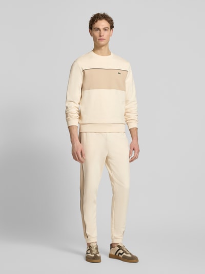 Männermodel trägt Regular Fit Sweatshirt aus reiner Baumwolle von Lacoste in Two Tone Optik mit Label Patch, Ganzkörperansicht von vorne.