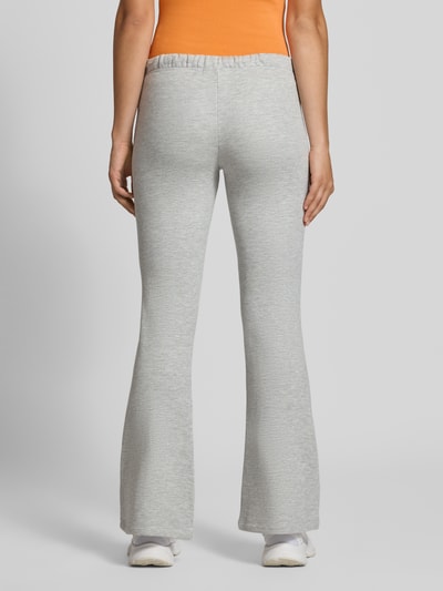 Frauenmodel trägt Flared Sweatpants aus reiner Baumwolle von REVIEW in Hellgrau mit elastischem Bund und seitlichen Eingrifftaschen, Ganzkörperansicht Rückansicht.